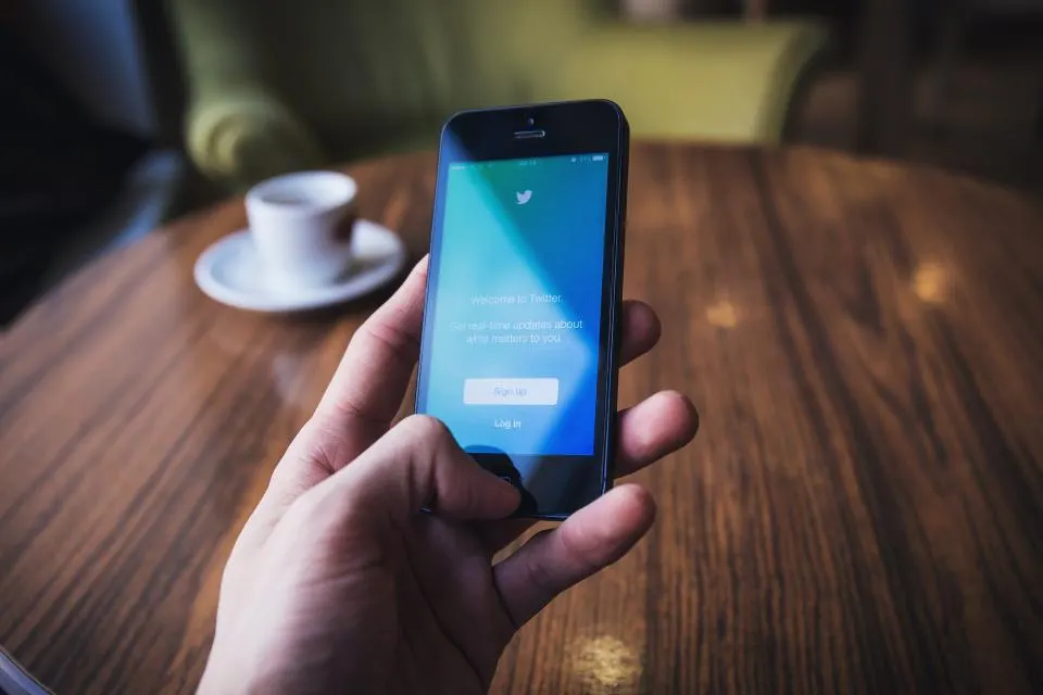 A phone lighting up in someone's hand beside a coffee cup