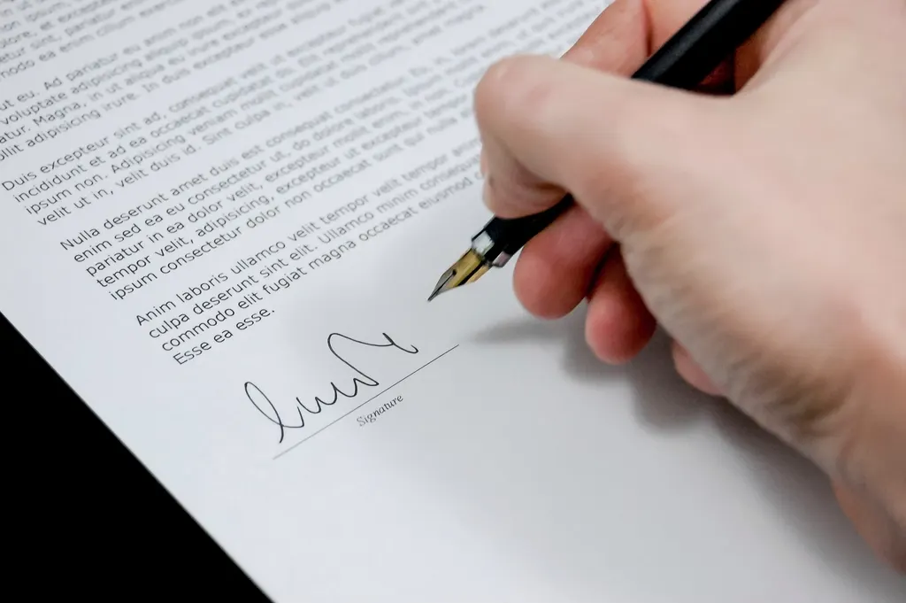 A hand signing a document with a fountain pen
