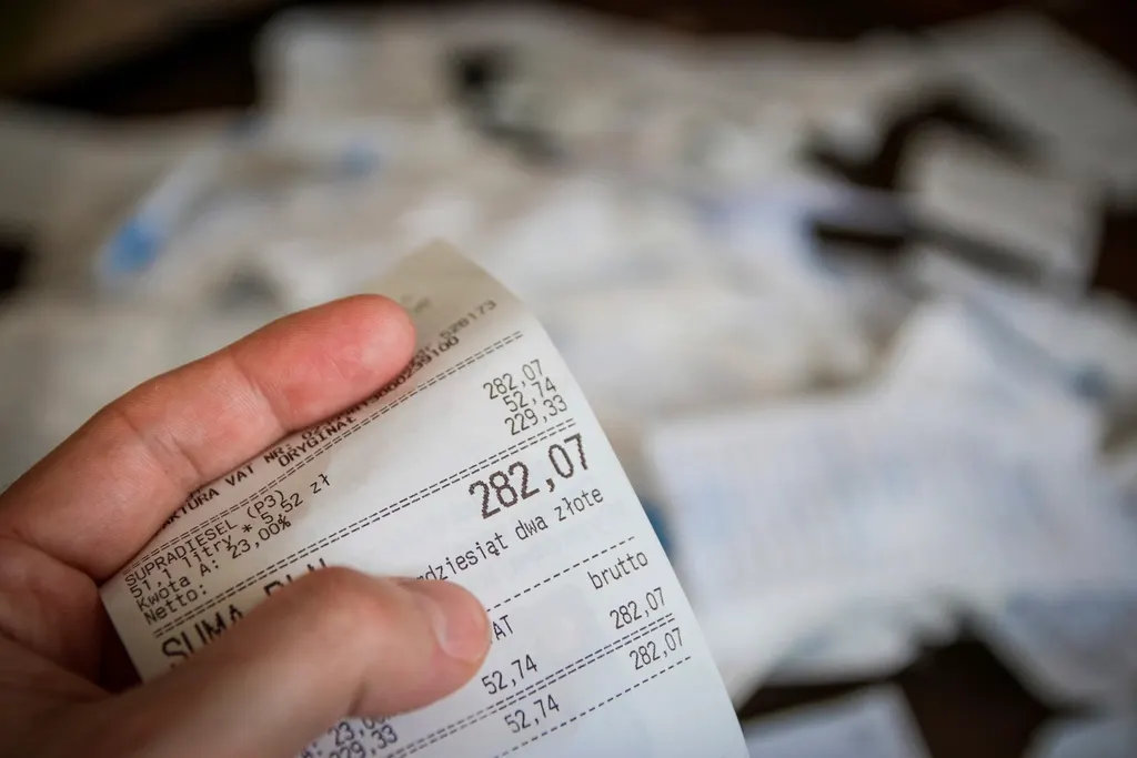 A hand holding a printed receipt