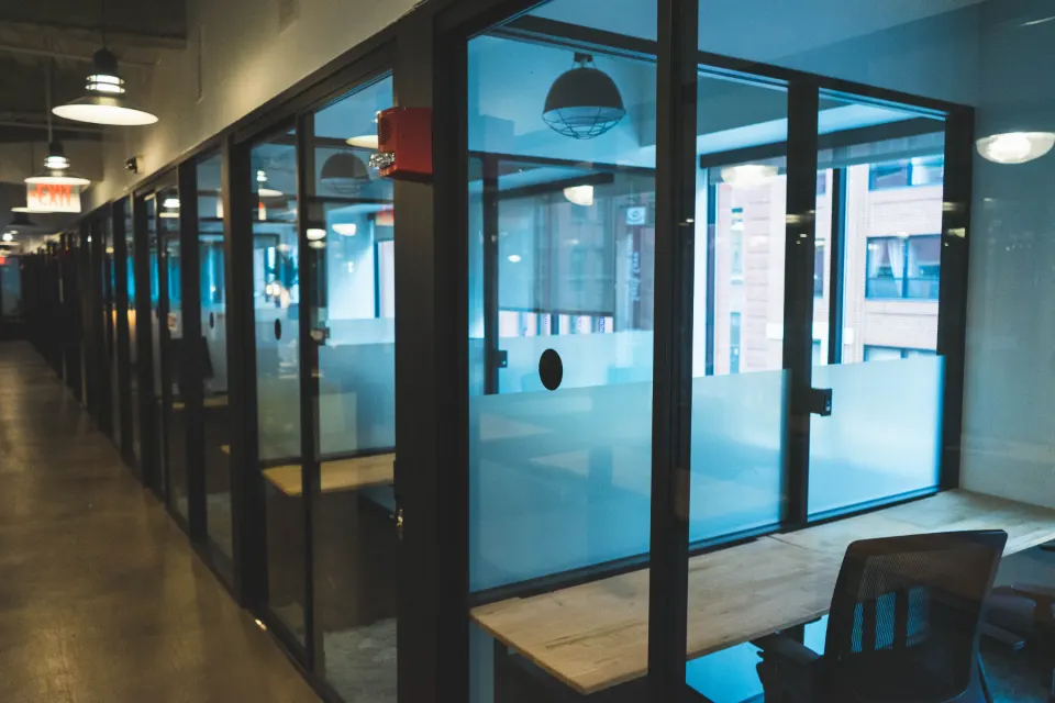 An empty office corridor lined with glass meeting rooms