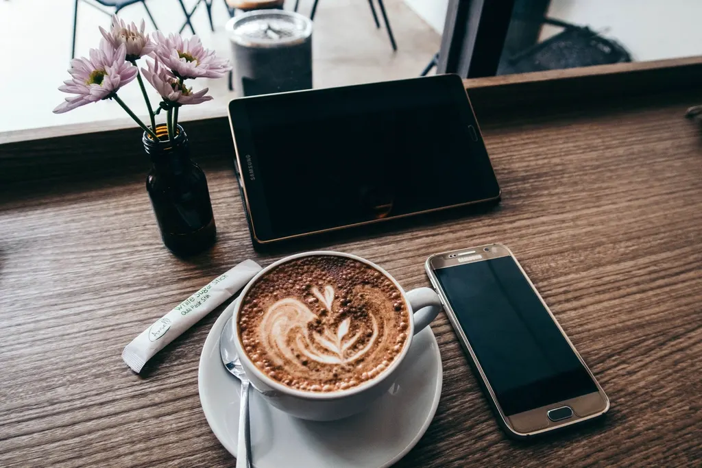 A tablet, phone and coffee on a café table