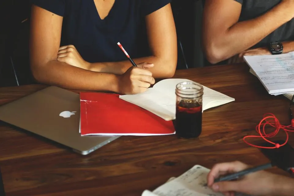 Two people at a meeting table with notes between them